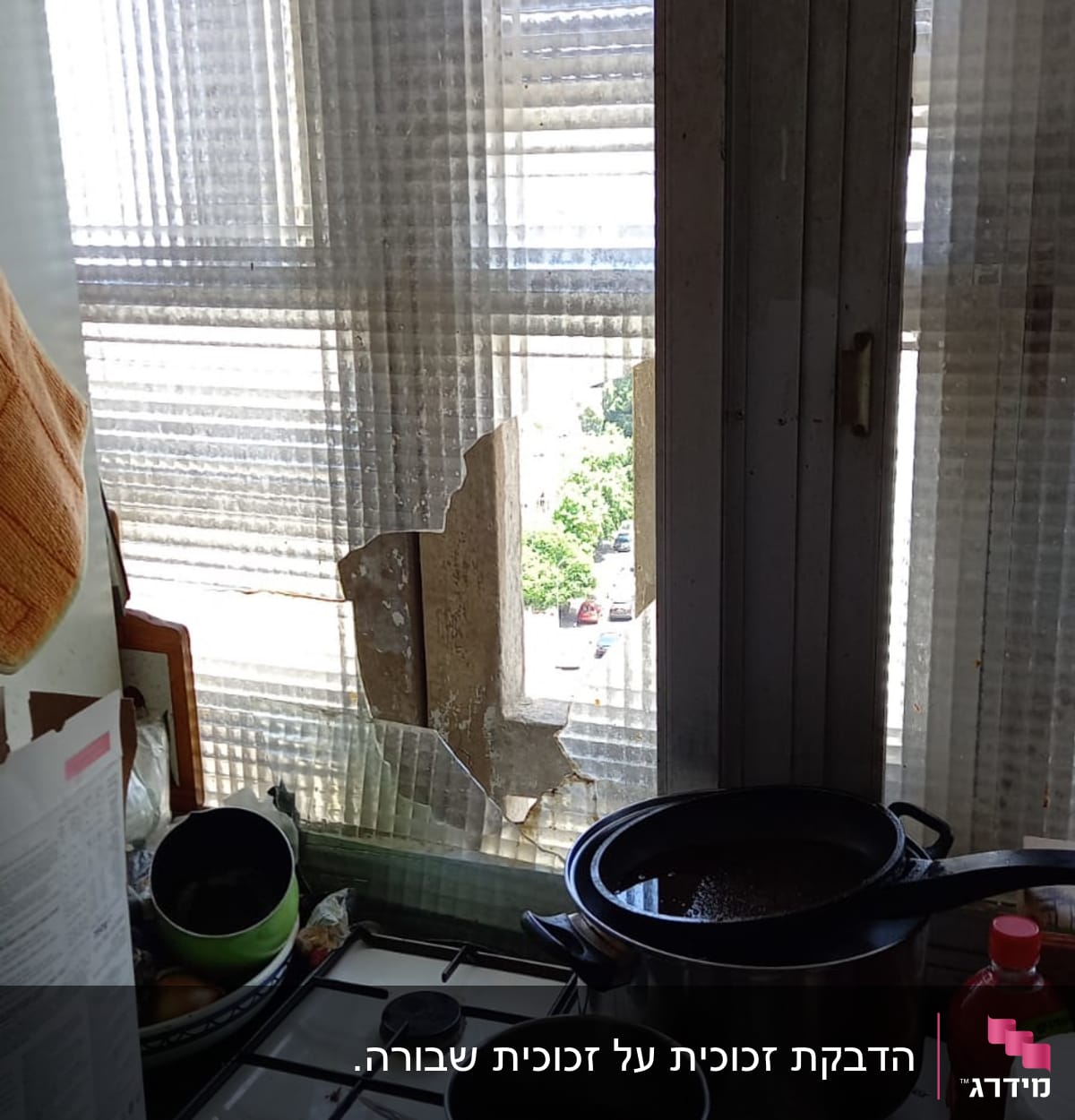 זכוכית שבורה בחלון מטבח עם סירים על הכיריים